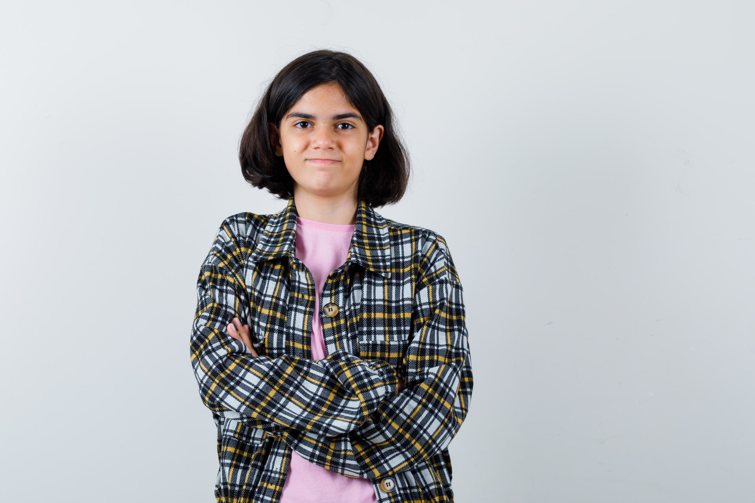 young-girl-checked-shirt-pink-t-shirt-standing-arms-crossed-looking-happy-min